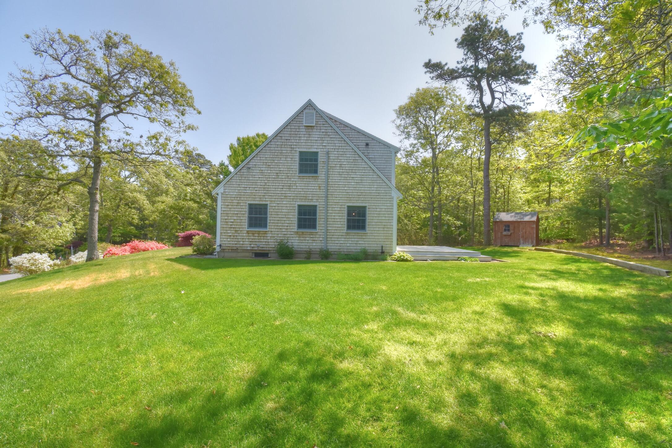 41 Turning Mill Road Brewster, MA 02631 - Photo 33 of 44 a backyard of a house with plants and large tree