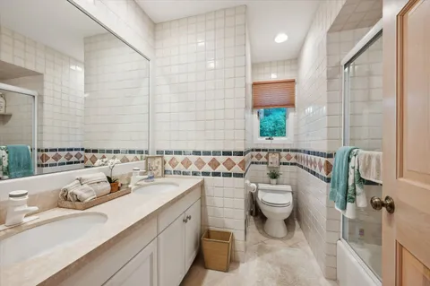 a bathroom with a double vanity sink toilet and a mirror