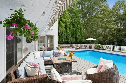 a view of a patio with couches potted plants and a large tree