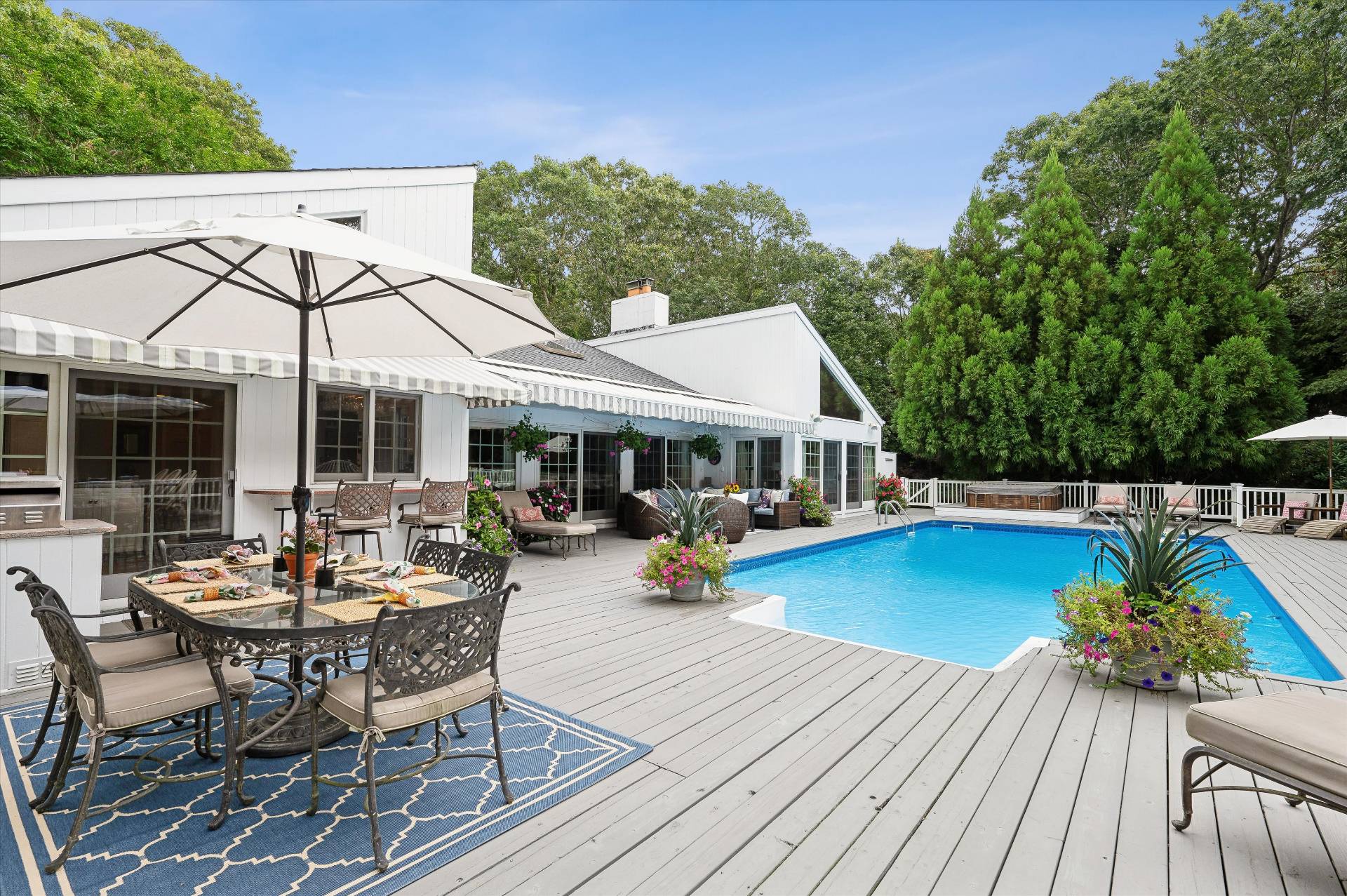 25 Midhampton Avenue Quogue, NY 11959 - Photo 7 of 32 a view of a patio with dining table and chairs under an umbrella with wooden floor