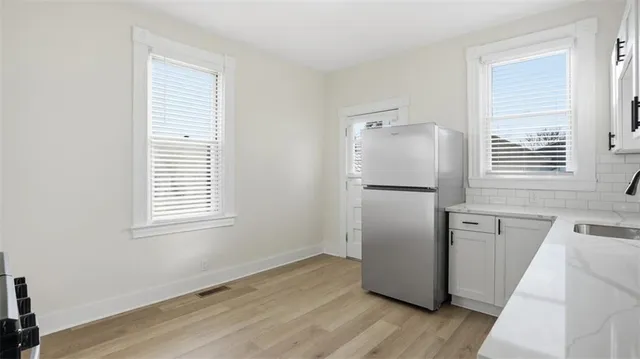 an empty room with wooden floor and a kitchen