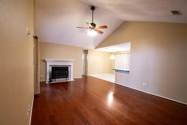 an empty room with wooden floor fireplace and window