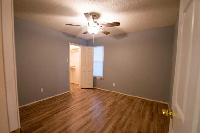an empty room with wooden floor fan and windows