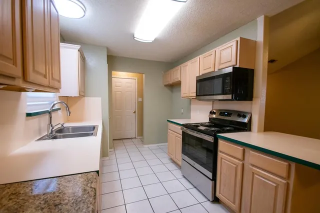 a kitchen with stainless steel appliances granite countertop a stove a sink and a microwave