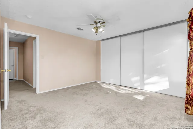 a view of an empty room with a chandelier fan