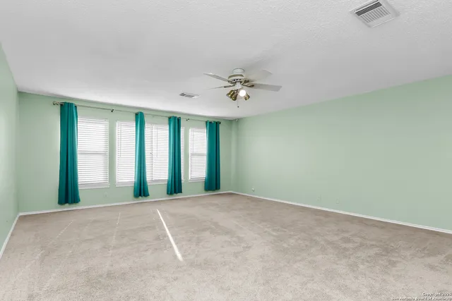 an empty room with a ceiling fan and a window