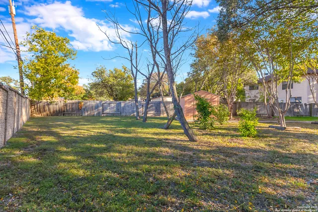 a view of yard with tree and wooden fence