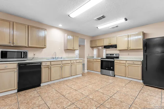 a kitchen with a refrigerator sink and cabinets
