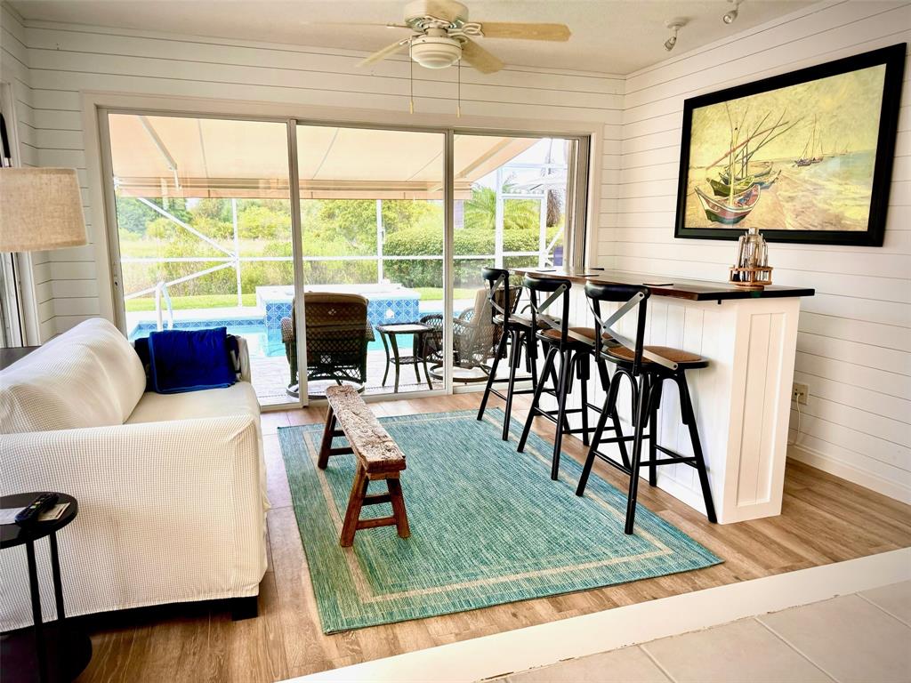 a view of a dining room with furniture one side kitchen view and wooden floor