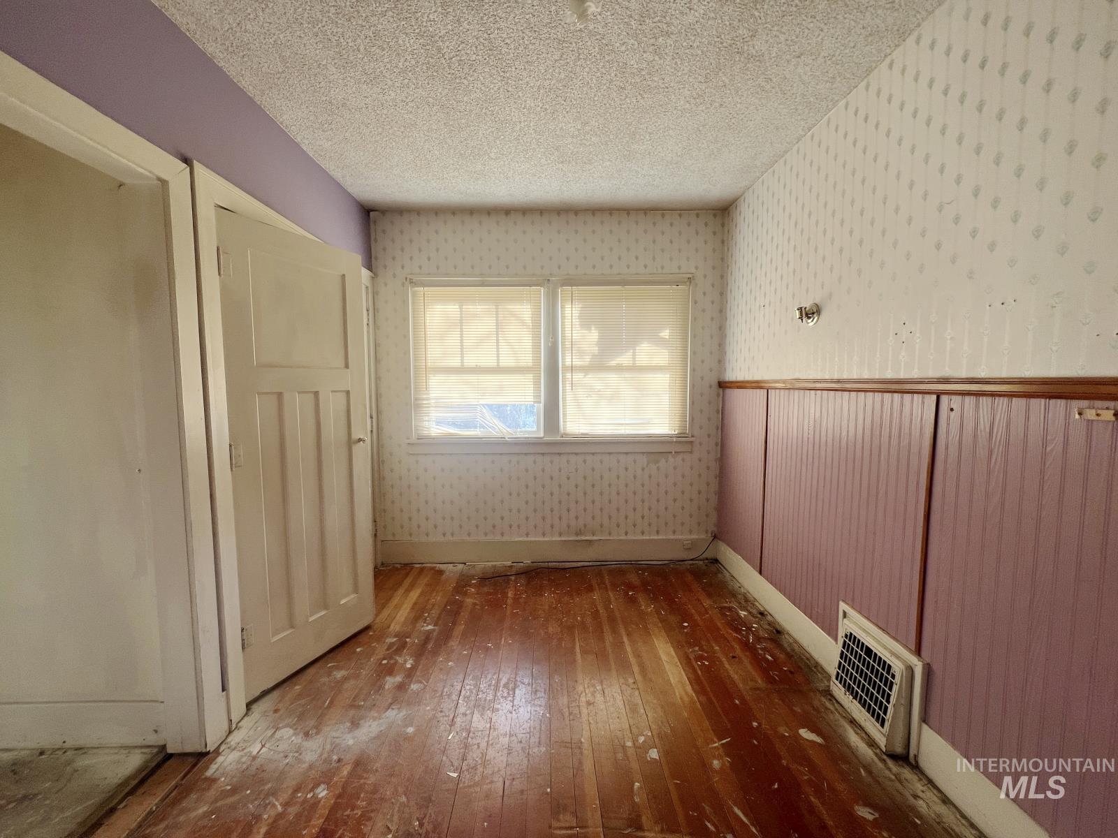1002 9th Street Clarkston, WA 99403 - Photo 12 of 19 Unfurnished room with hardwood / wood-style floors, wallpapered walls, and a textured ceiling