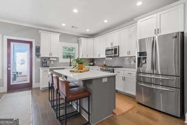 a kitchen with stainless steel appliances granite countertop a refrigerator a stove a sink a microwave and a refrigerator