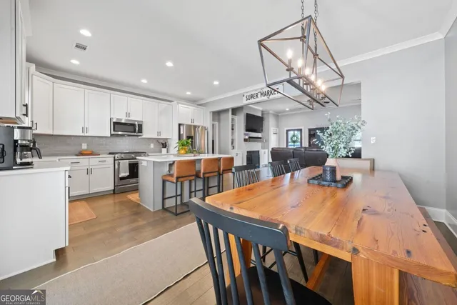 a open dining room with stainless steel appliances kitchen island granite countertop a dining table chairs and a refrigerator