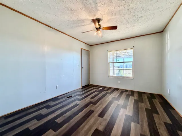 an empty room with wooden floor fan and windows