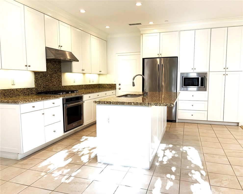 178 Working Ranch Irvine, CA 92602 - Photo 9 of 42 a kitchen with stainless steel appliances kitchen island granite countertop a sink a stove a refrigerator a microwave oven with white cabinets