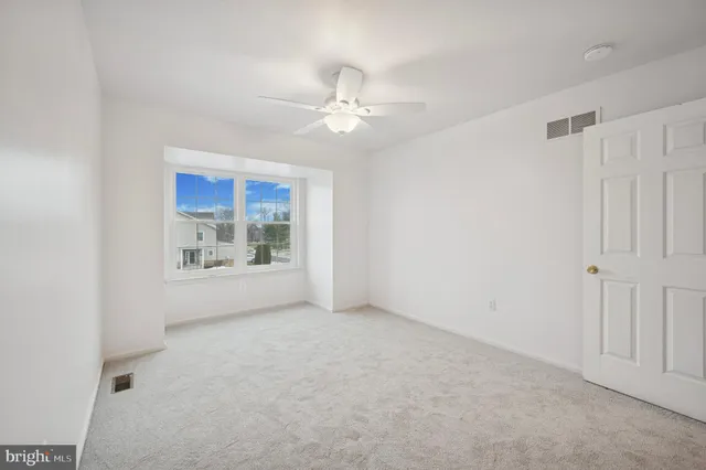 an empty room with a ceiling fan and a window