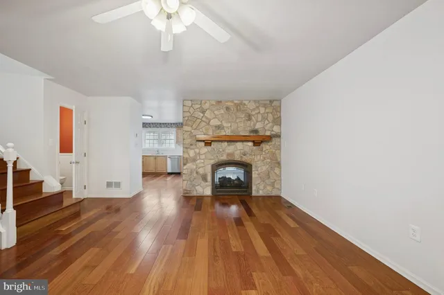 a view of a livingroom with wooden floor a fireplace and windows