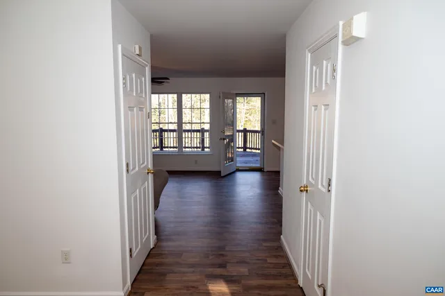 a view of a hallway with wooden floor and a bathroom