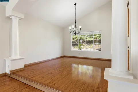 a view of empty room with wooden floor and window