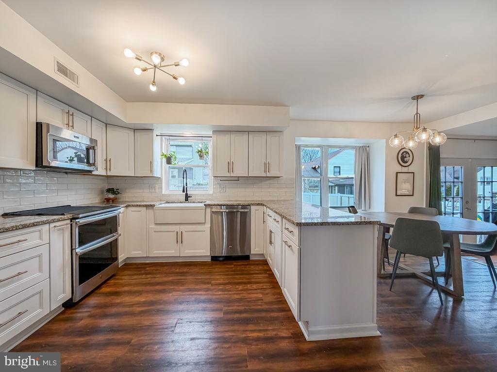 738 Bridgeview Road Feasterville-Trevose, PA 19053 - Photo 17 of 54 a kitchen with granite countertop a stove top oven a sink dishwasher a dining table and chairs with wooden floor