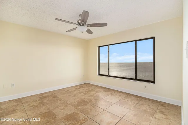 an empty room with windows and fan