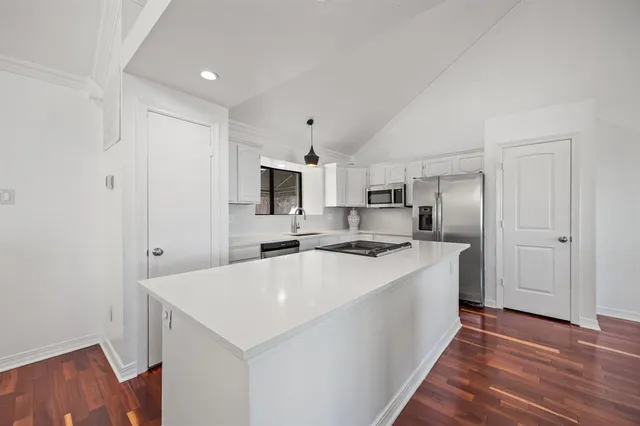 a kitchen with a sink a stove a refrigerator and white cabinets