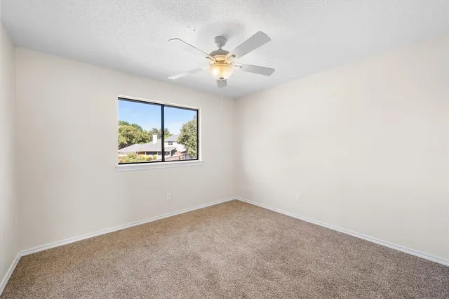 an empty room with window and ceiling fan