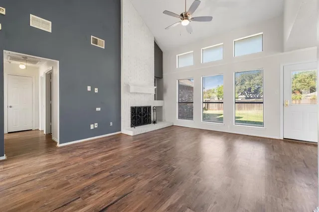 an empty room with wooden floor fireplace and windows