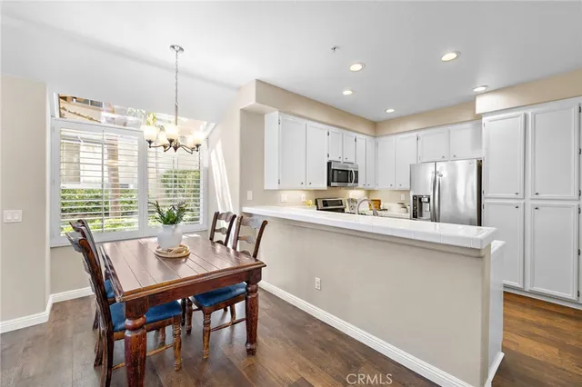 a kitchen with stainless steel appliances granite countertop a dining table chairs refrigerator sink and cabinets