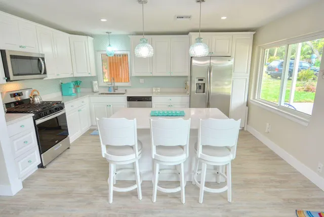 a kitchen with granite countertop stainless steel appliances white cabinets and wooden floor