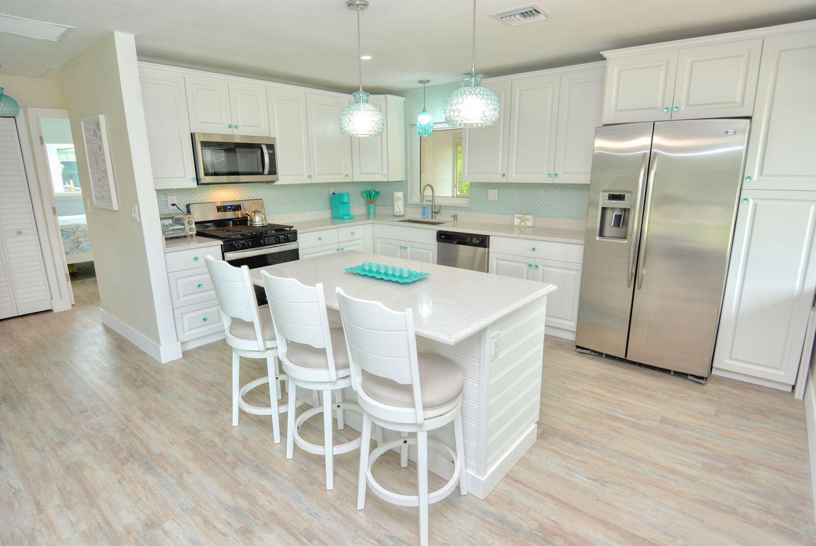 1315 Northeast Flora Place Jensen Beach, FL 34957 - Photo 14 of 27 a kitchen with stainless steel appliances a dining table chairs refrigerator and microwave