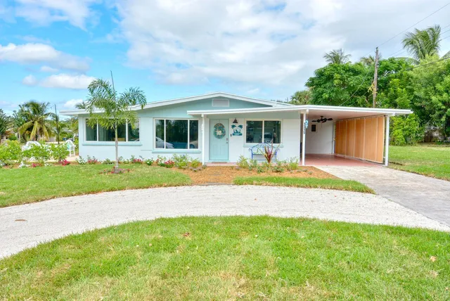 a front view of a house with a yard and potted plants