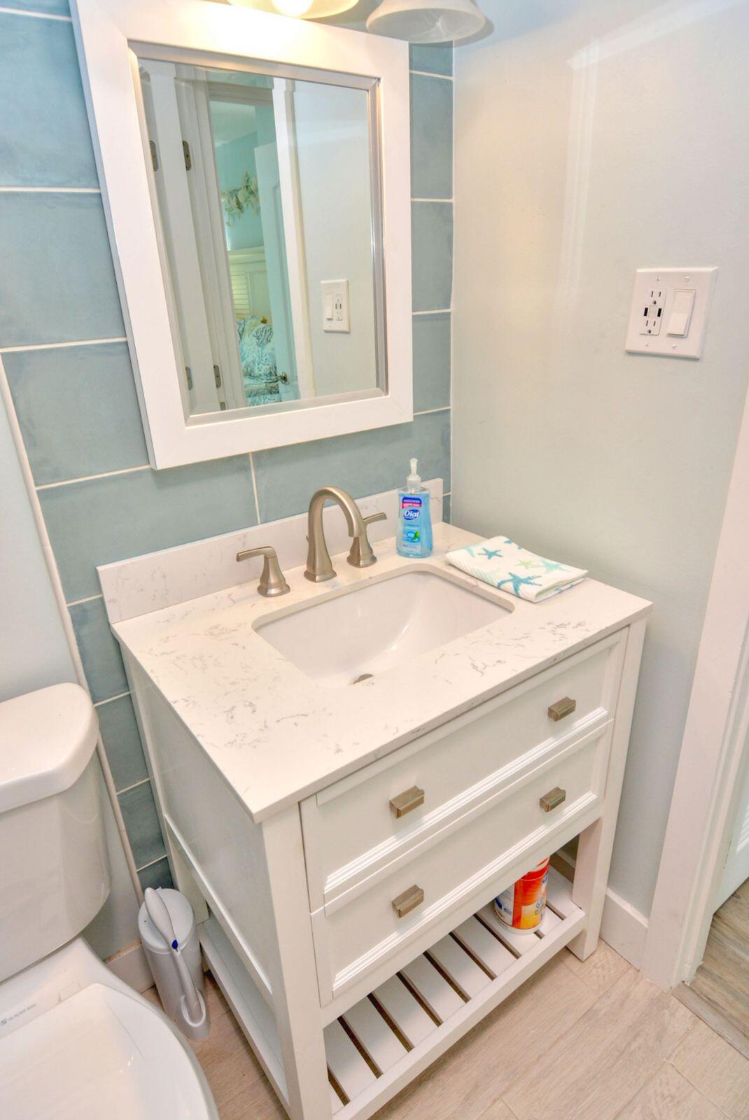 1315 Northeast Flora Place Jensen Beach, FL 34957 - Photo 25 of 27 a bathroom with a sink a toilet and a mirror
