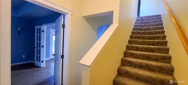 a view of staircase with white walls and white door