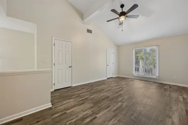 an empty room with wooden floor and windows