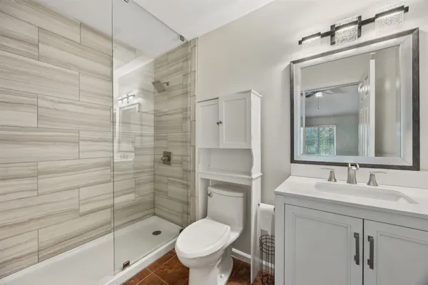 a bathroom with a toilet sink vanity and shower