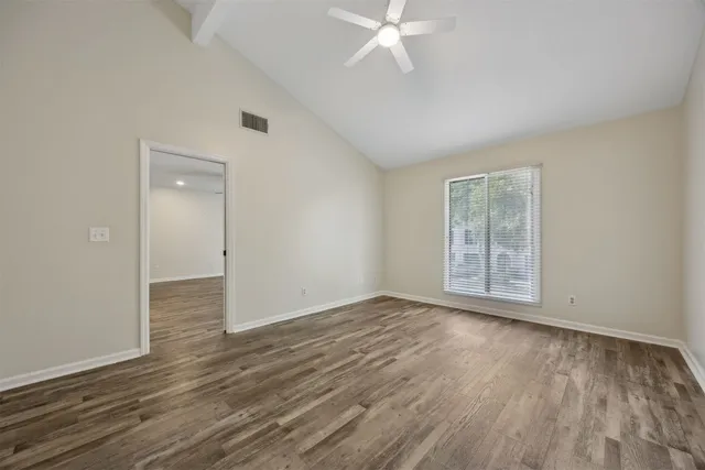 an empty room with wooden floor and windows
