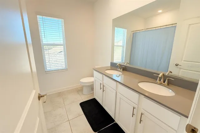 a bathroom with a double vanity sink a mirror and a toilet