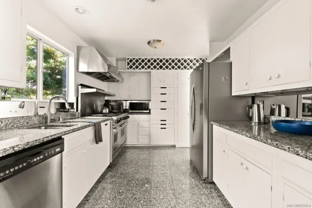 a kitchen with granite countertop a sink stainless steel appliances and window