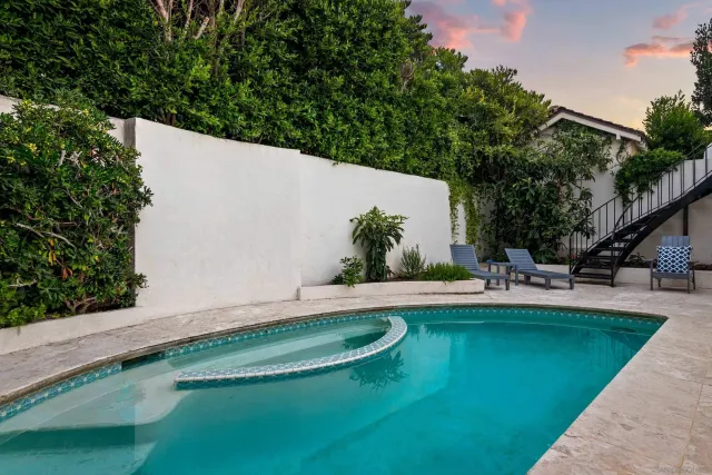 a view of a swimming pool with lawn chairs under an umbrella