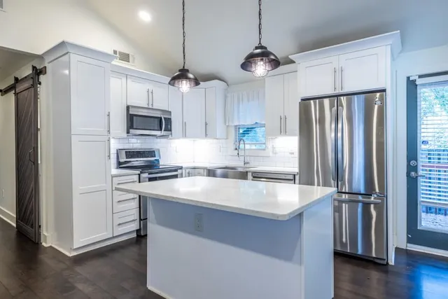 a kitchen with kitchen island a sink appliances a counter space and a window