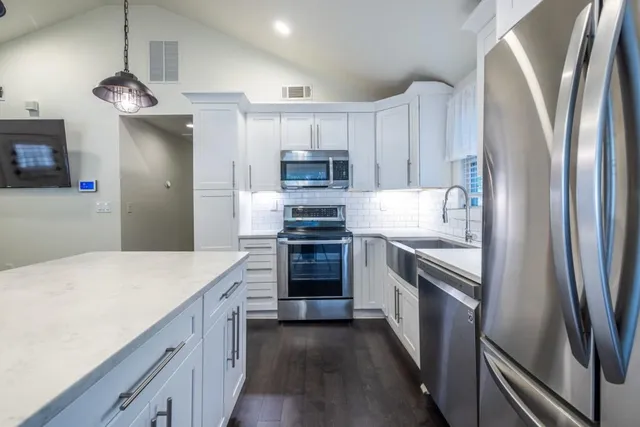 a kitchen with kitchen island a counter top space stainless steel appliances and cabinets