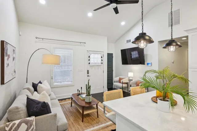 a living room with furniture a flat screen tv and a chandelier