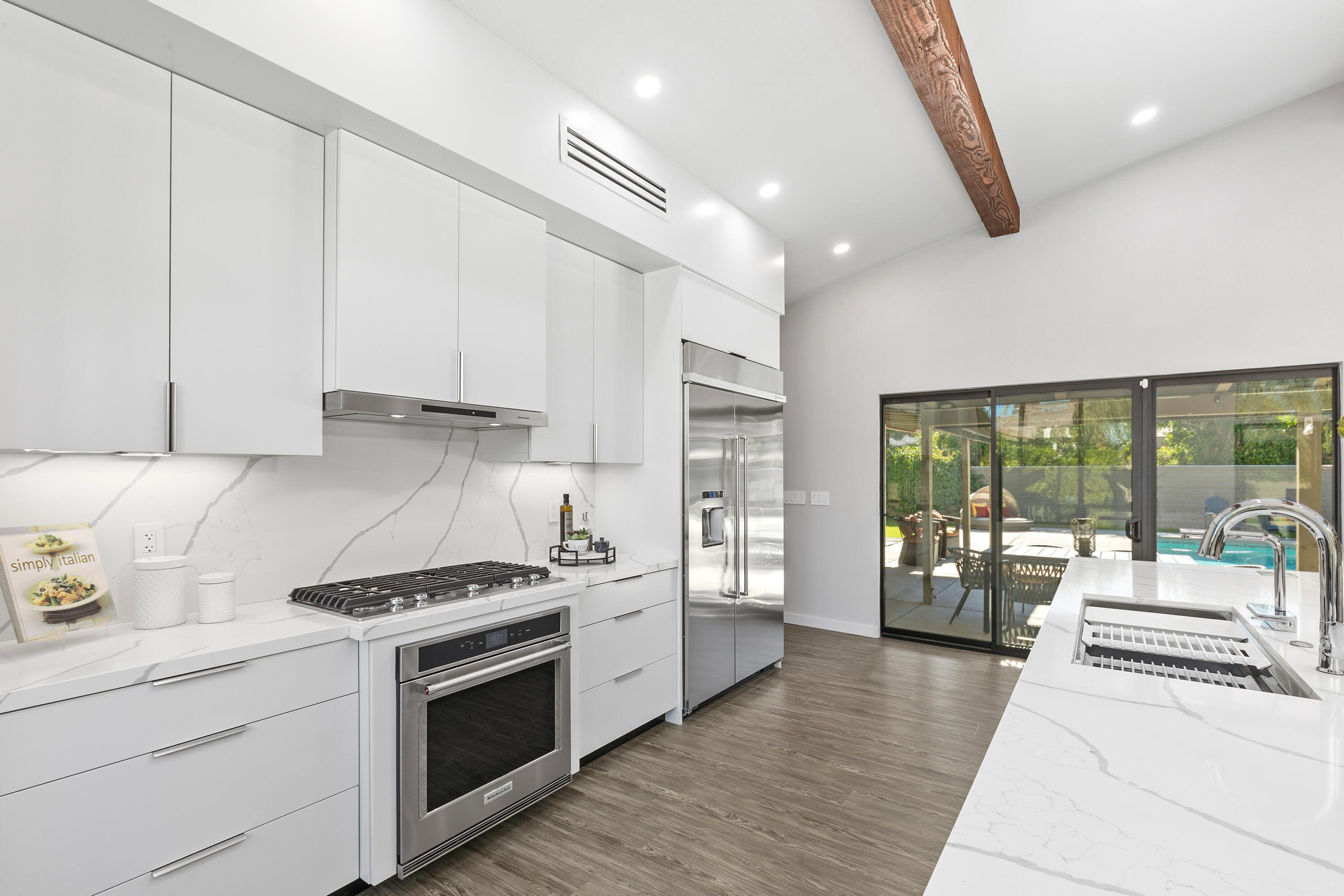 74155 Mockingbird Trail Indian Wells, CA 92210 - Photo 18 of 55 a kitchen with a stove a sink and white cabinets with wooden floor next to windows