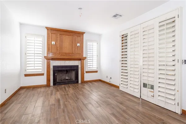 an empty room with wooden floor fireplace and windows