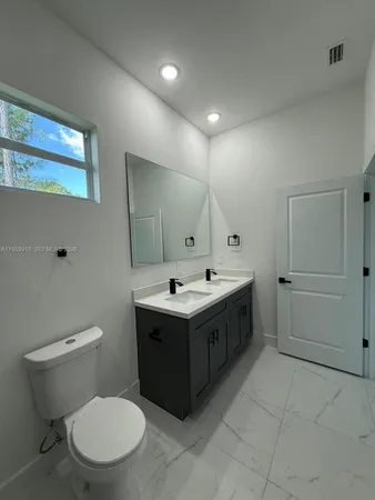 a bathroom with a sink vanity mirror and toilet