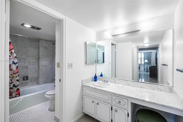 a bathroom with a granite countertop sink a toilet and shower