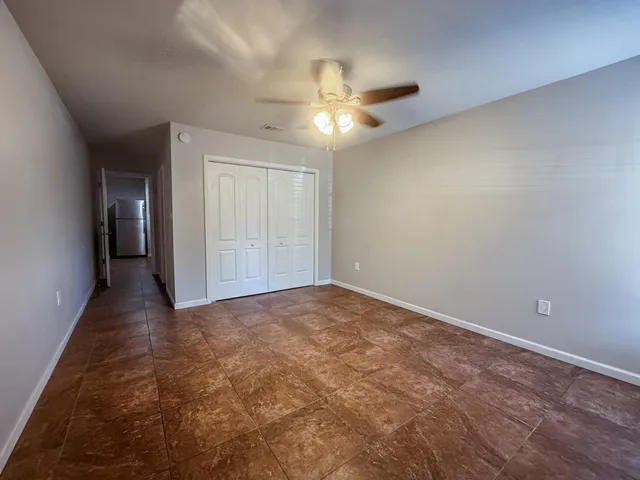an empty room with closet and a chandelier fan