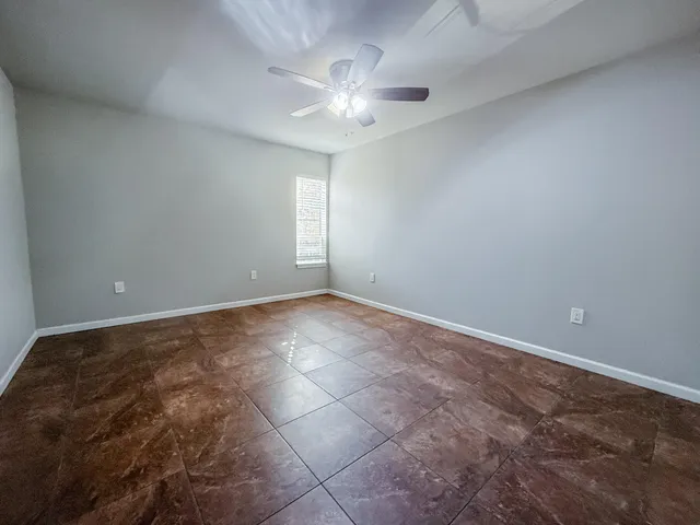an empty room with a chandelier fan and windows