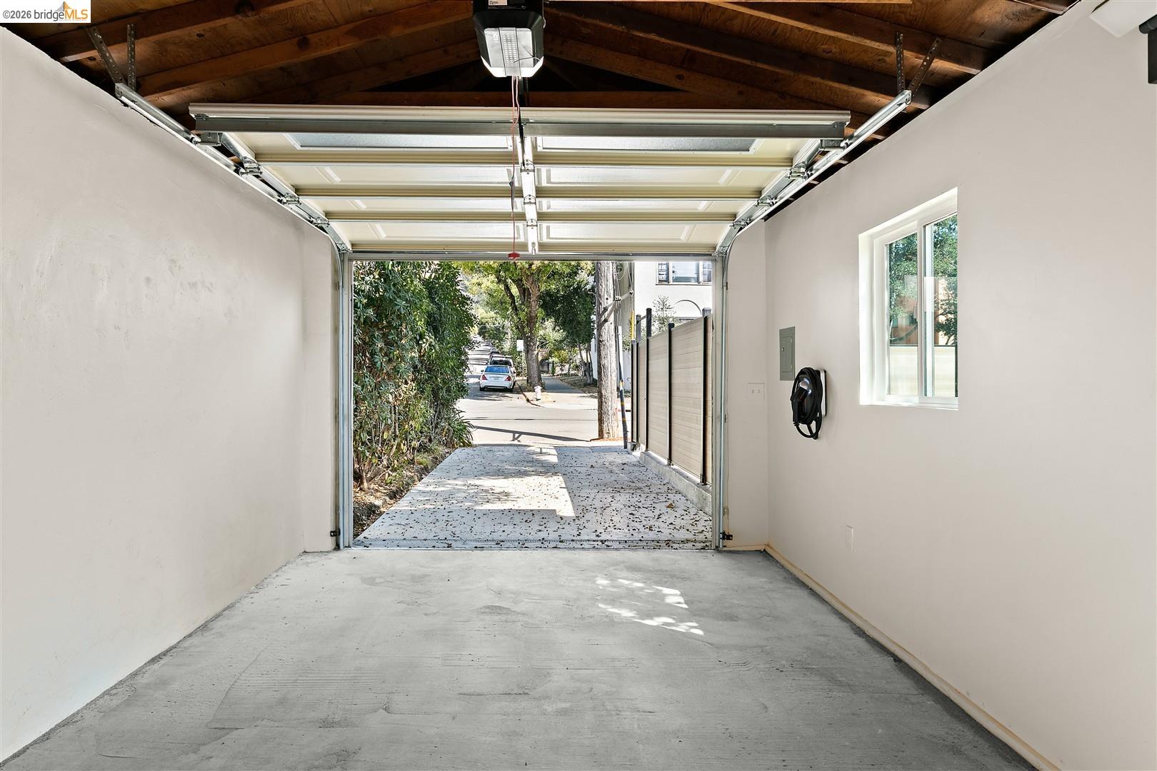 1668 Arch Street Berkeley, CA 94709 - Photo 53 of 78 Open-concept garage with exposed wood beam ceiling, concrete flooring, and a white framed window