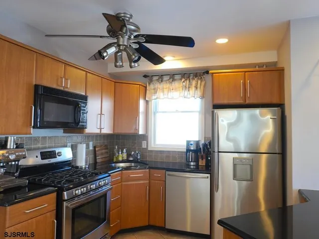 a kitchen with stainless steel appliances granite countertop a refrigerator a sink a stove a microwave and wooden floors